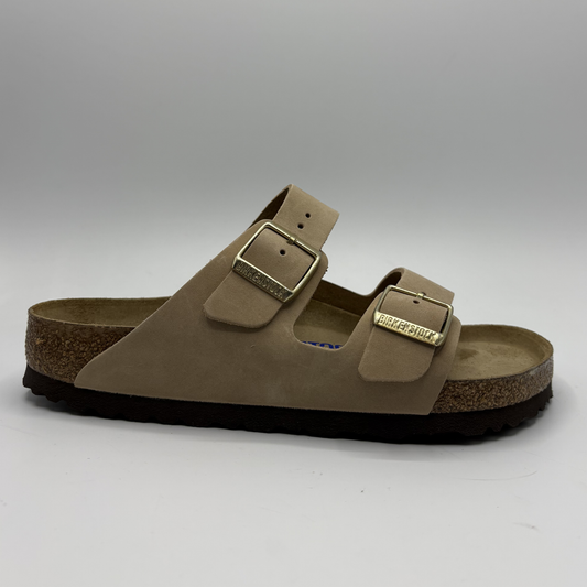 Brown sandal with gold buckle on a gray background