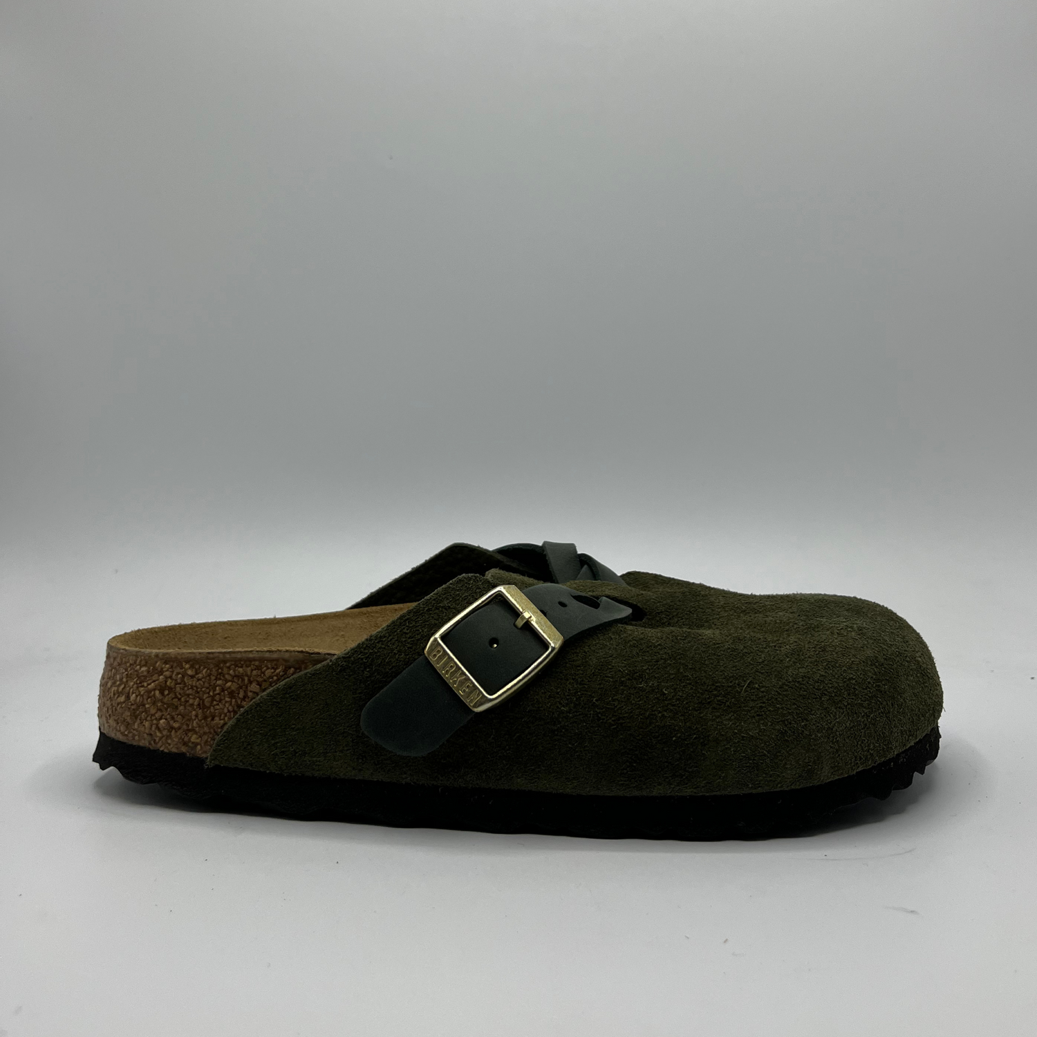 Green clog shoe with a strap and buckle on a gray background