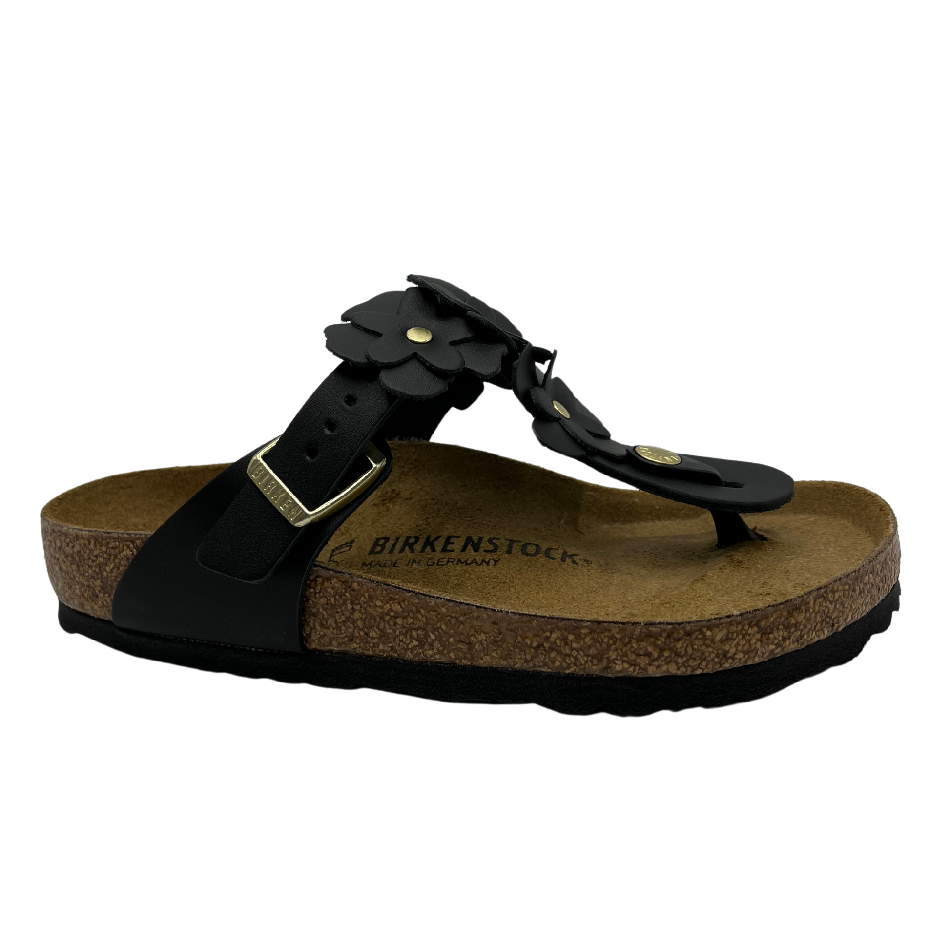 45 degree angled view of black leather sandals with flower shaped details and adjustable strap