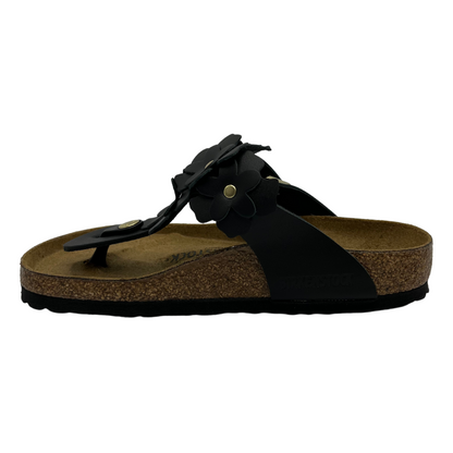 Left facing view of black leather sandals with flower shaped details and adjustable strap