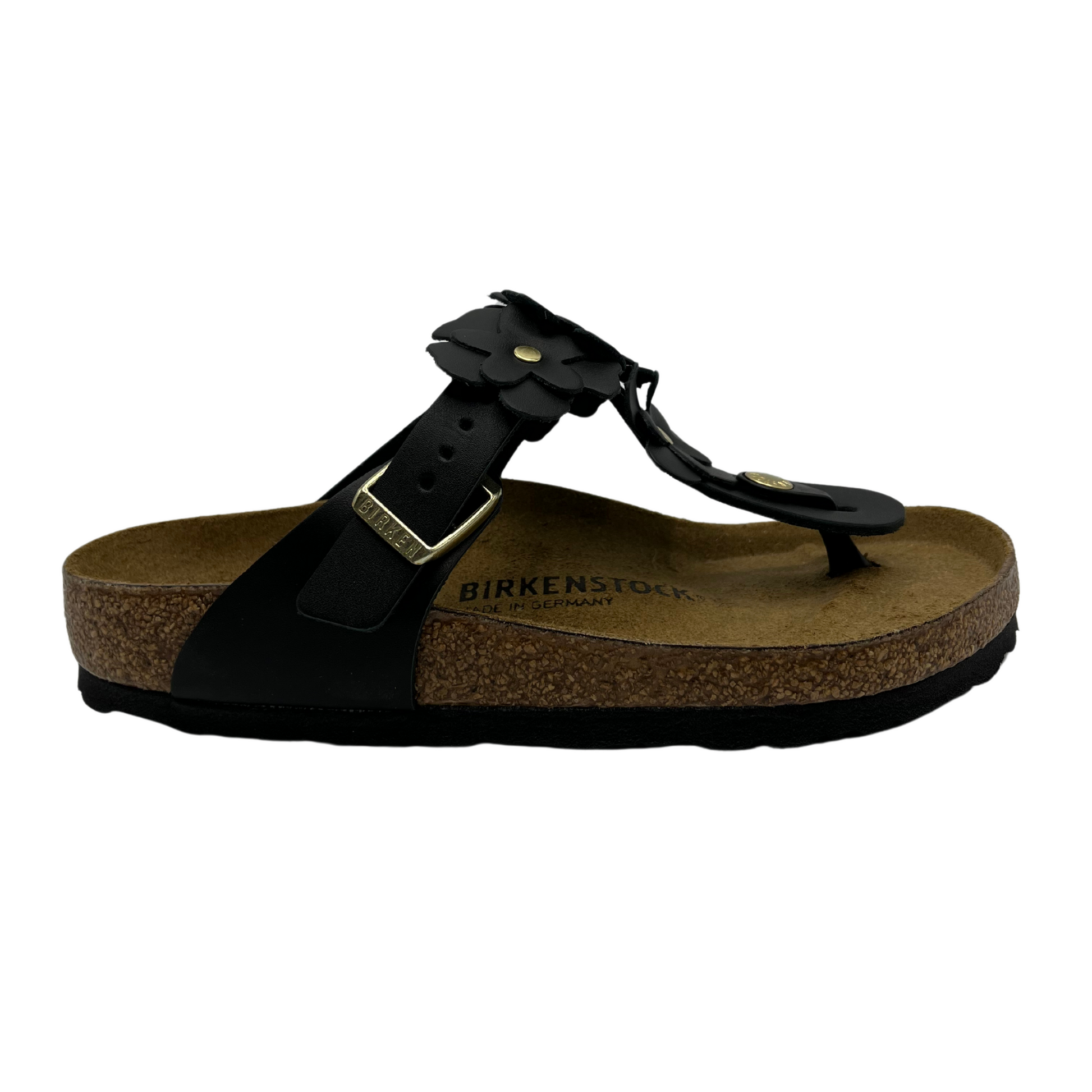 Right facing view of black leather sandals with flower shaped details and adjustable strap