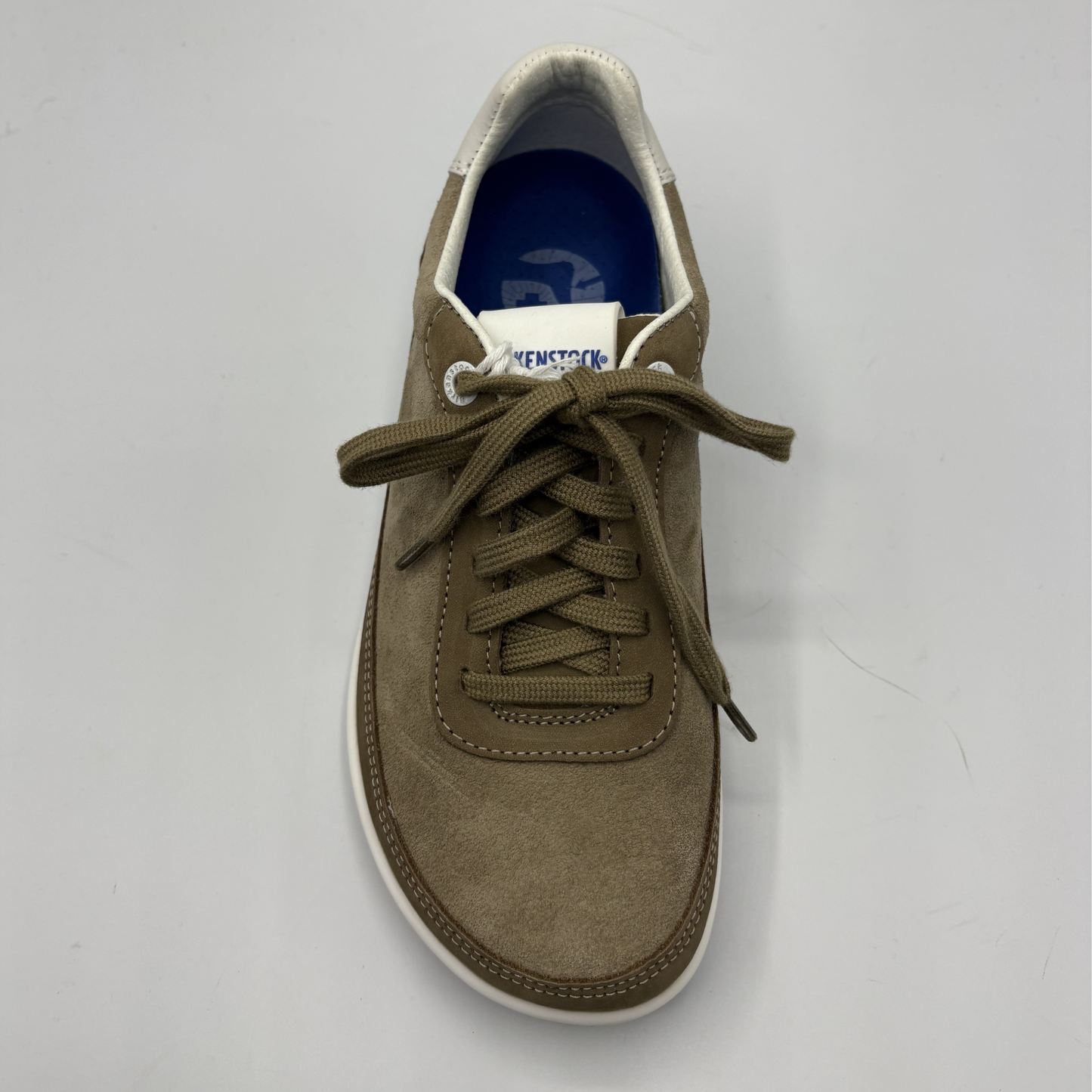 Brown sneaker with white sole on a gray background