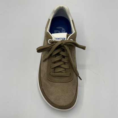 Brown sneaker with white sole on a gray background