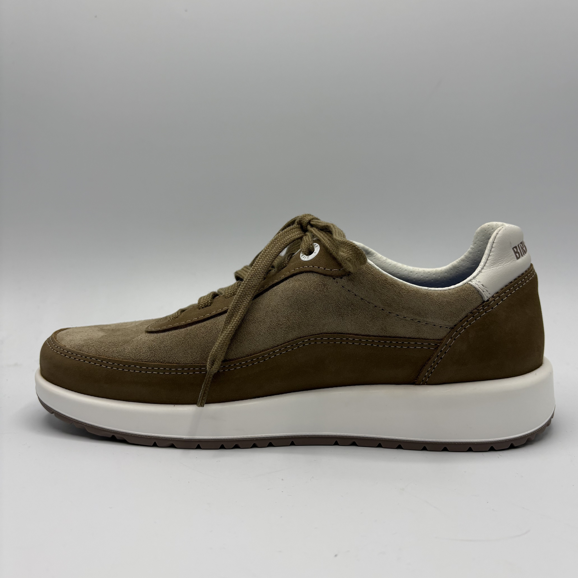 Brown sneaker with white sole on a gray background