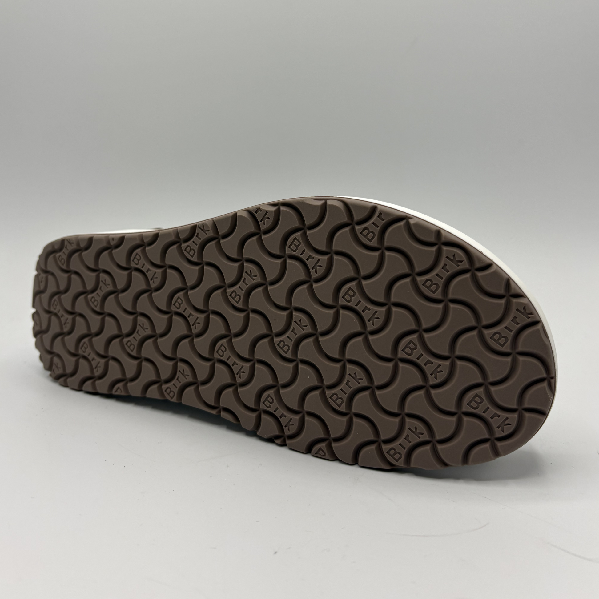 Brown shoe sole with wavy pattern on a white background