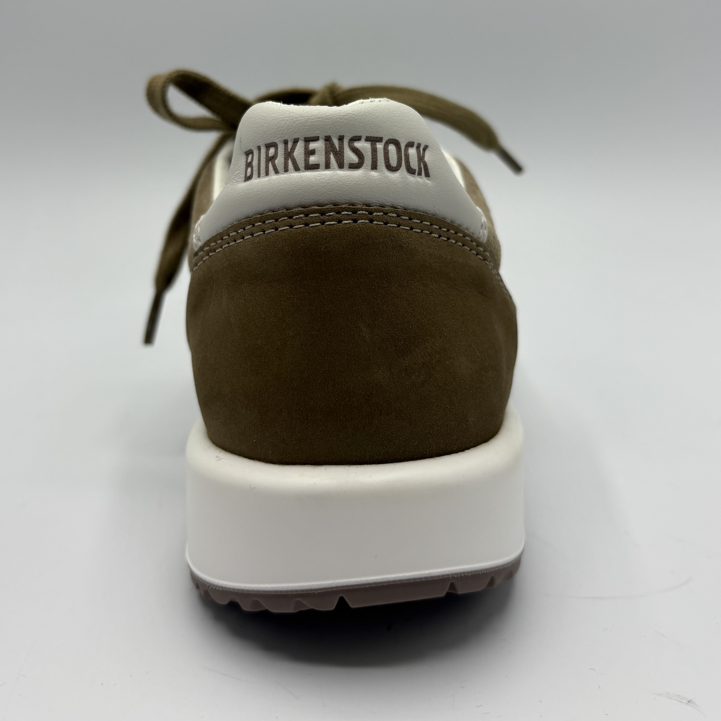 Brown sneaker with white sole on a light gray background