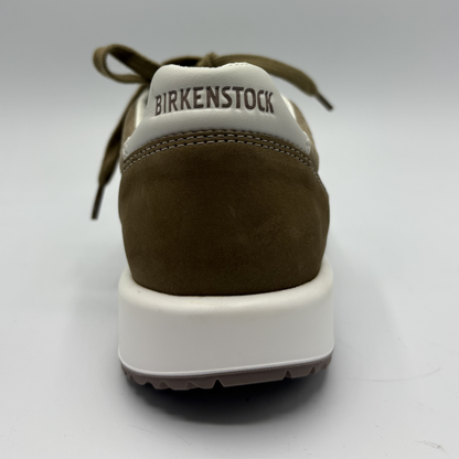 Brown sneaker with white sole on a light gray background