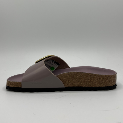 Left facing view of a faded purple slip on sandal with a big gold buckle on the strap. Featuring a lined,  contoured cork footbed