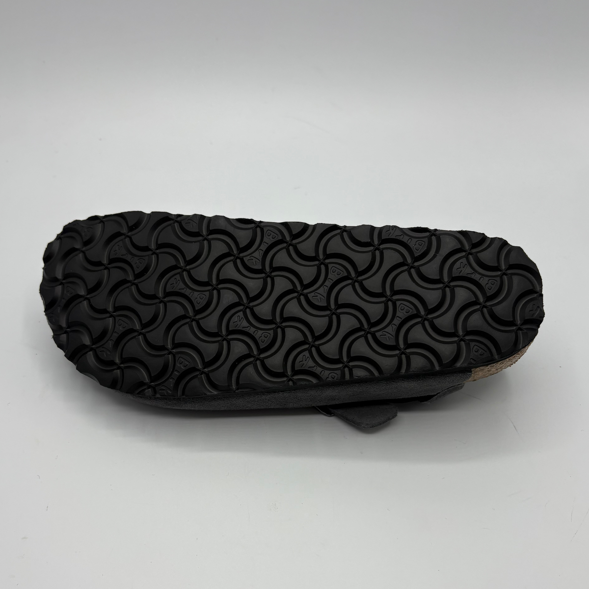 Bottom view of a charcoal slip on shoe with two adjustable buckle straps on a white background