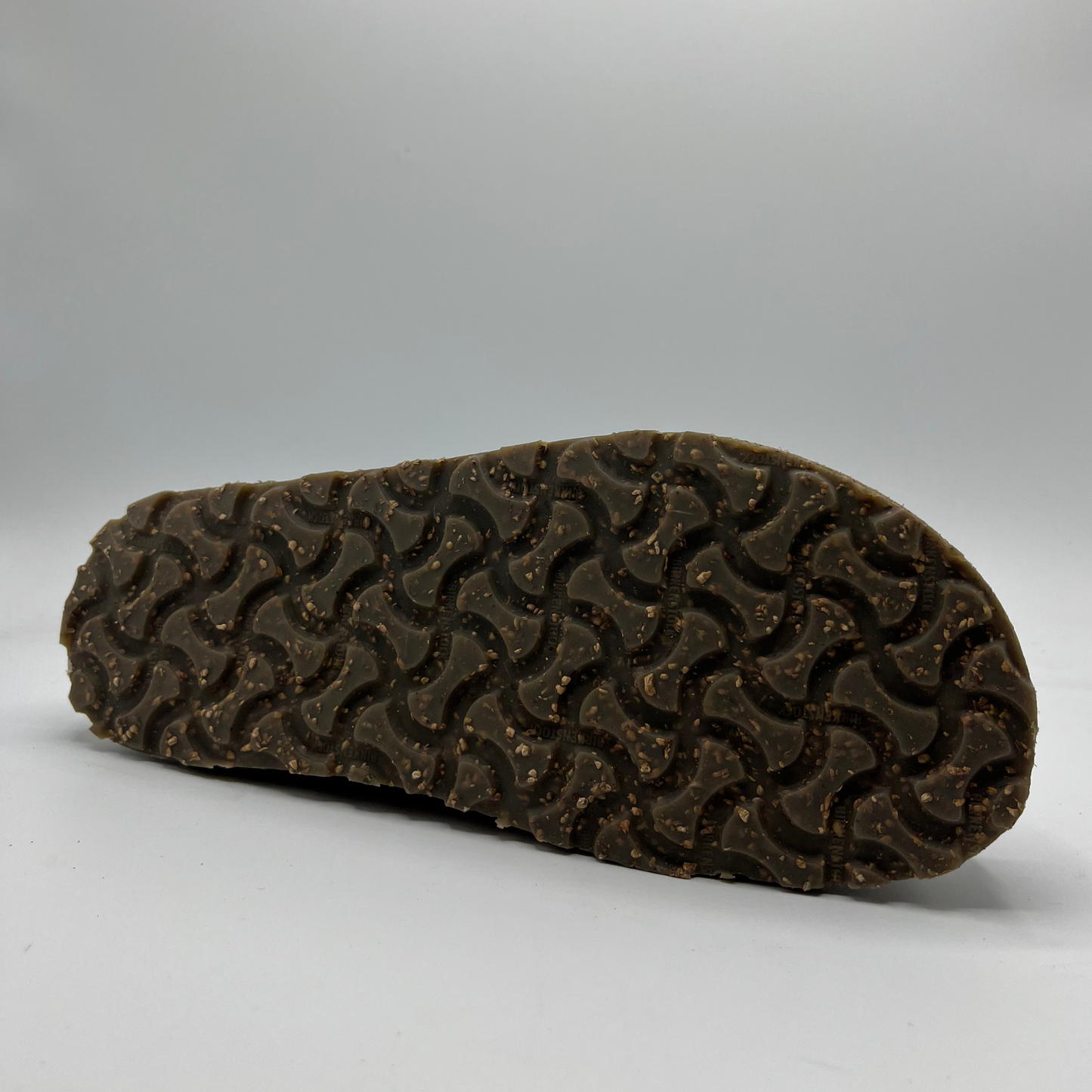 Brown sole of a shoe with tread pattern on a gray background