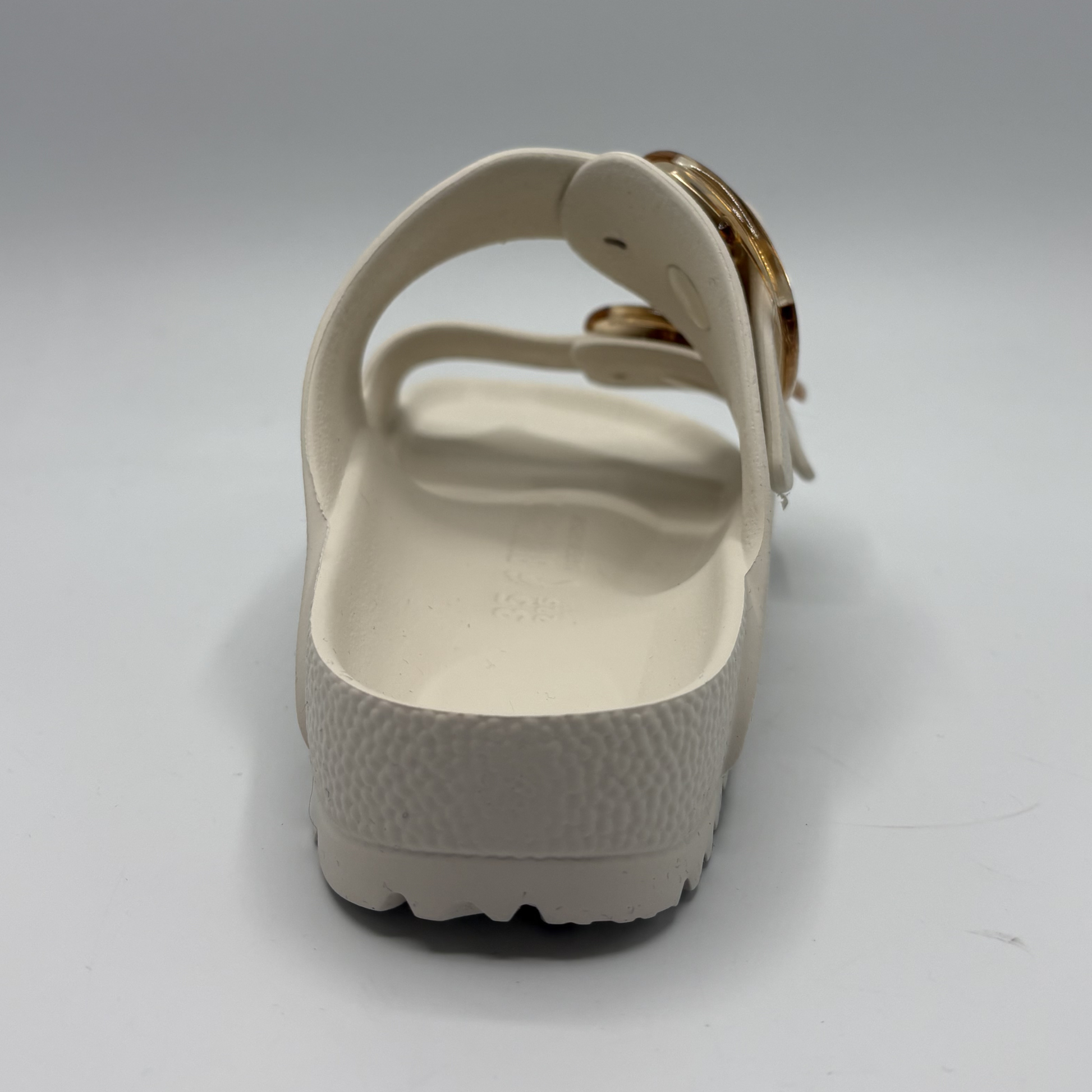 Eggshell sandal with a gold buckle on a white background