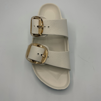 Eggshell sandal with gold buckles on a gray background