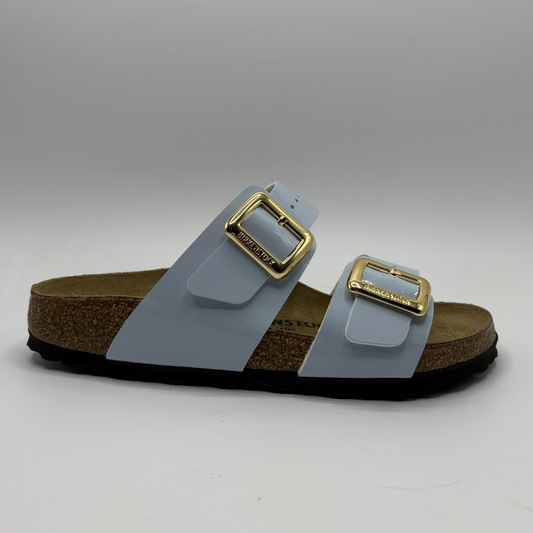 Sandal with gold buckles on a gray background