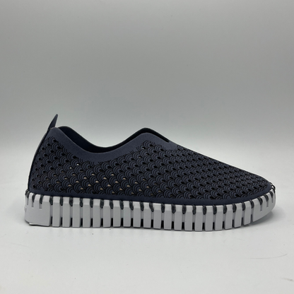 Right facing view of blue grey slip on shoe with an intricate laser cut upper and white rubber outsole.