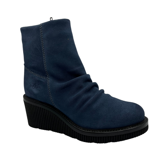 45 degree angled view of denim blue short bootie with slouched front, side zipper closure and black wedge heel.