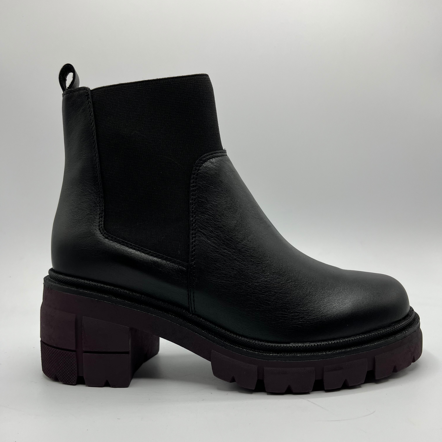 Black leather boot with thick sole on a light gray background