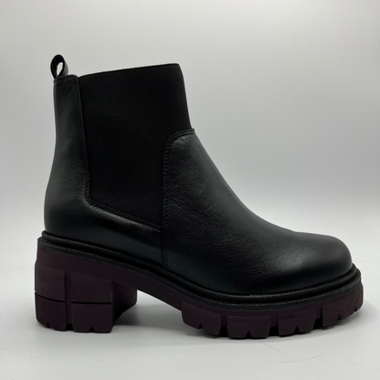 Black leather boot with thick sole on a light gray background