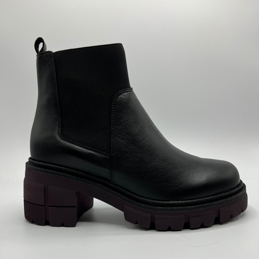 Black leather boot with thick sole on a light gray background