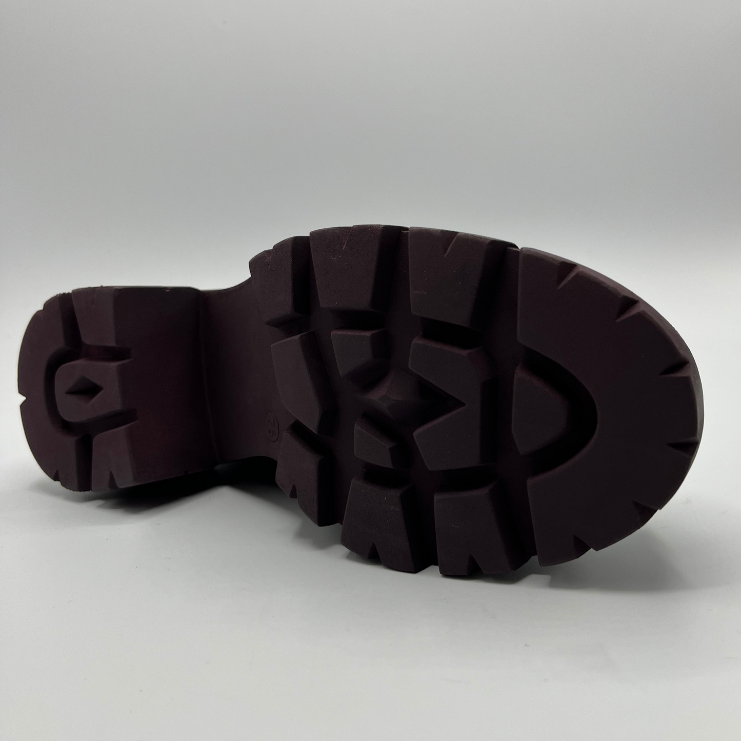 Close-up of a dark brown rubber sole on a light gray background