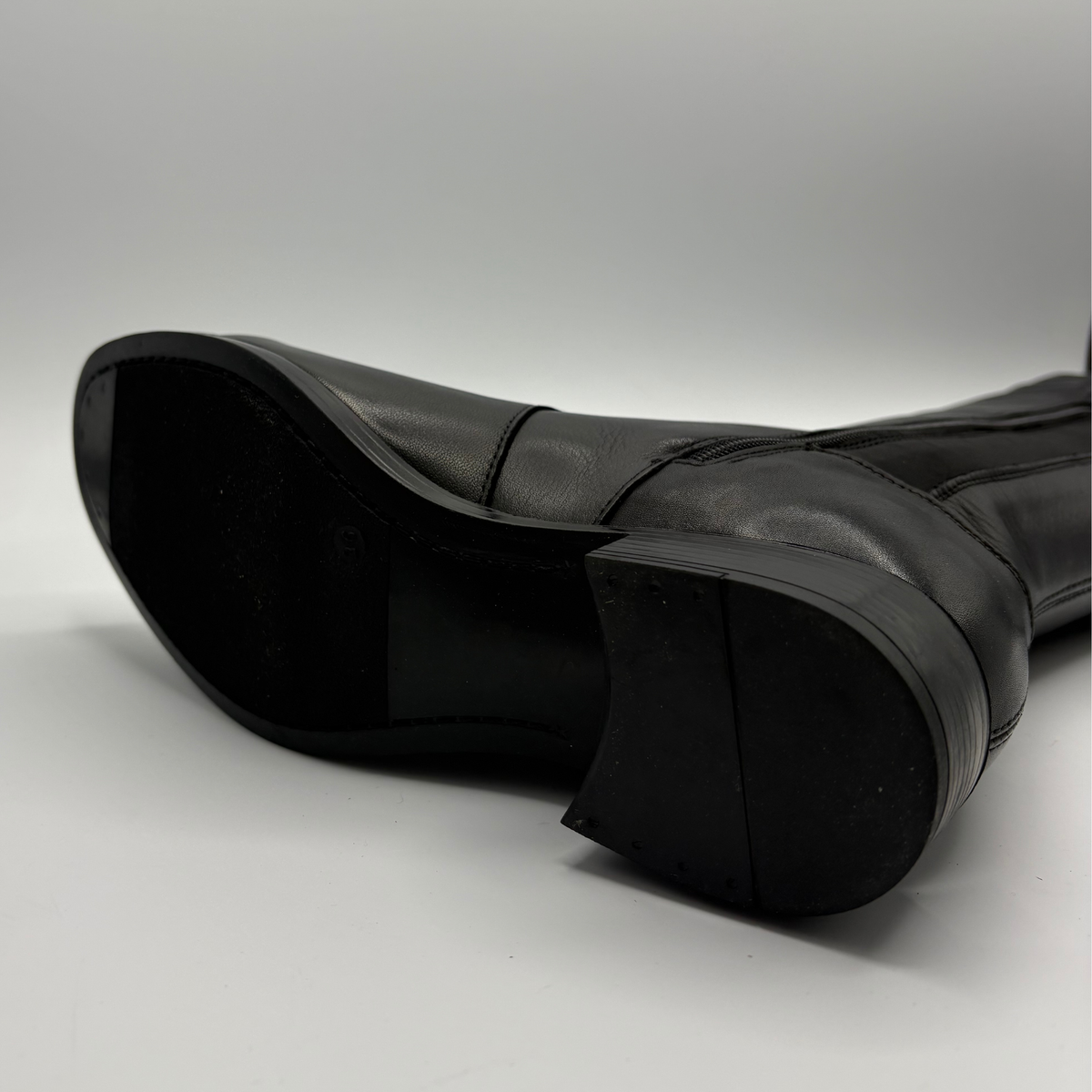 Bottom view of a black leather boot with an elasticated back panel on a white background