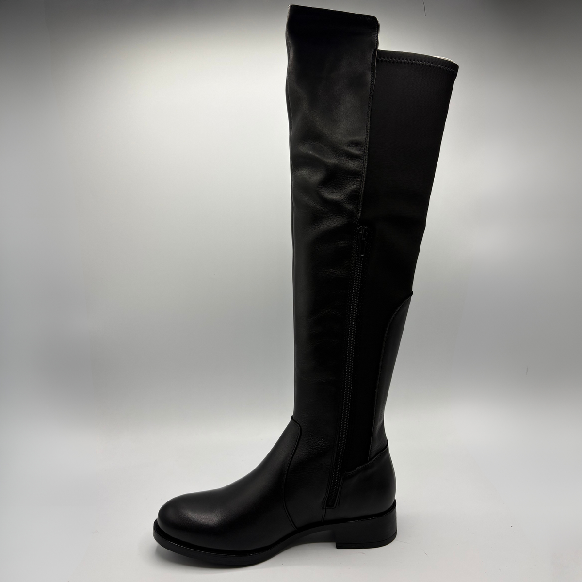Left facing view of a black leather boot with an elasticated back panel on a white background