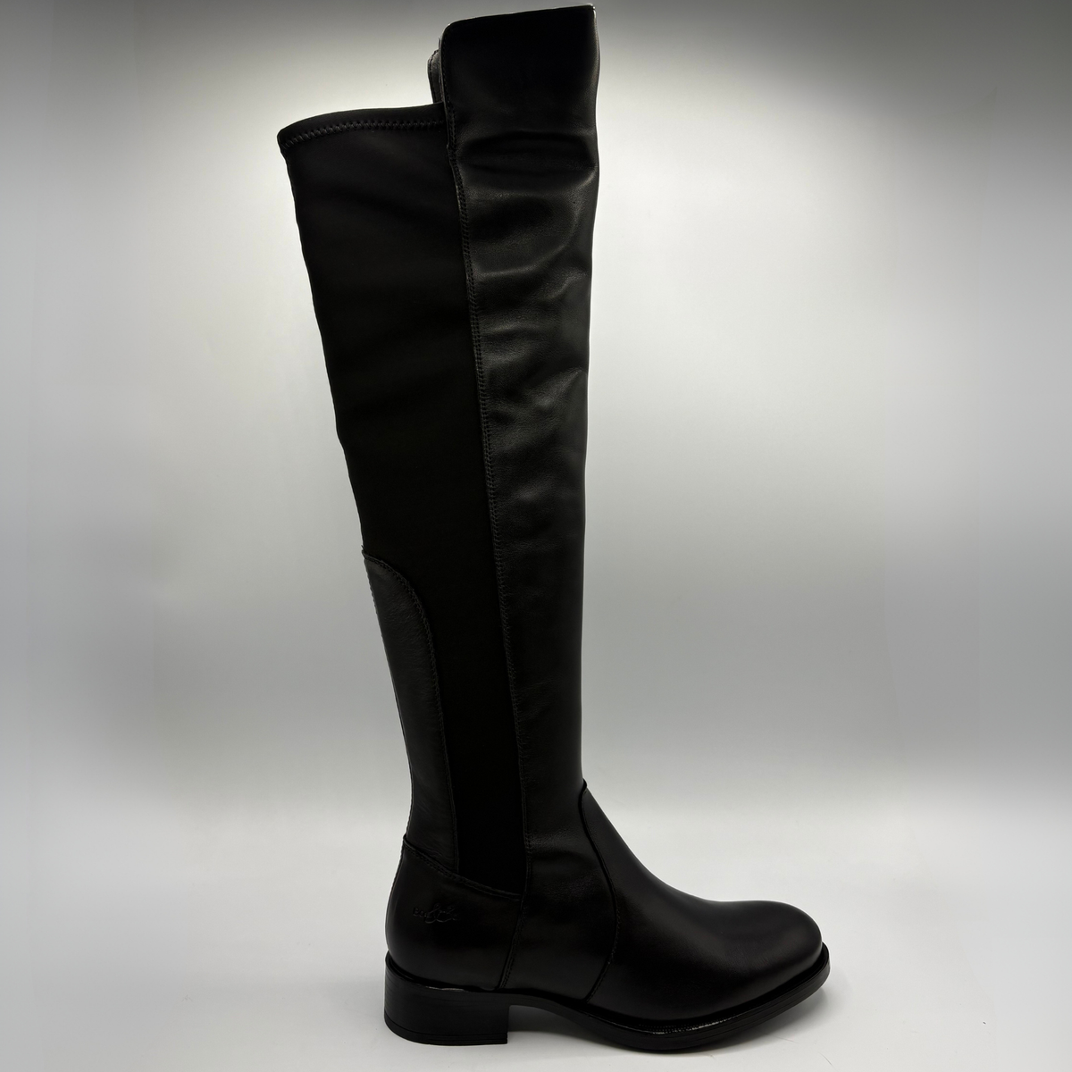 Right facing view of a black leather boot with an elasticated back panel on a white background