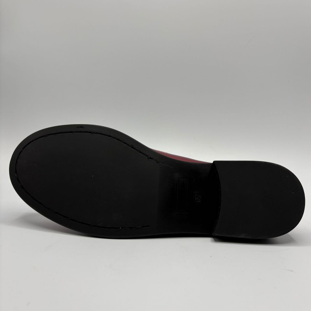 The black rubber outsole of a shoe, photographed from underneath against a light gray studio background.