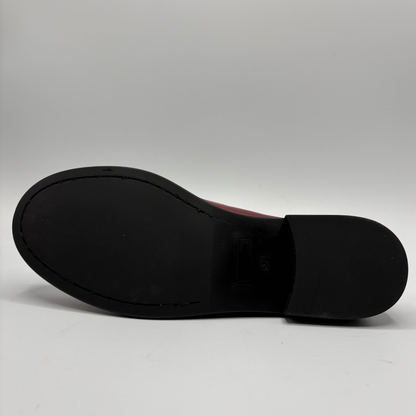 The black rubber outsole of a shoe, photographed from underneath against a light gray studio background.