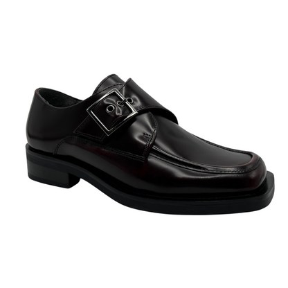 45 degree angled view of bordo leather loafer with silver buckle on upper, low heel and leather lining.