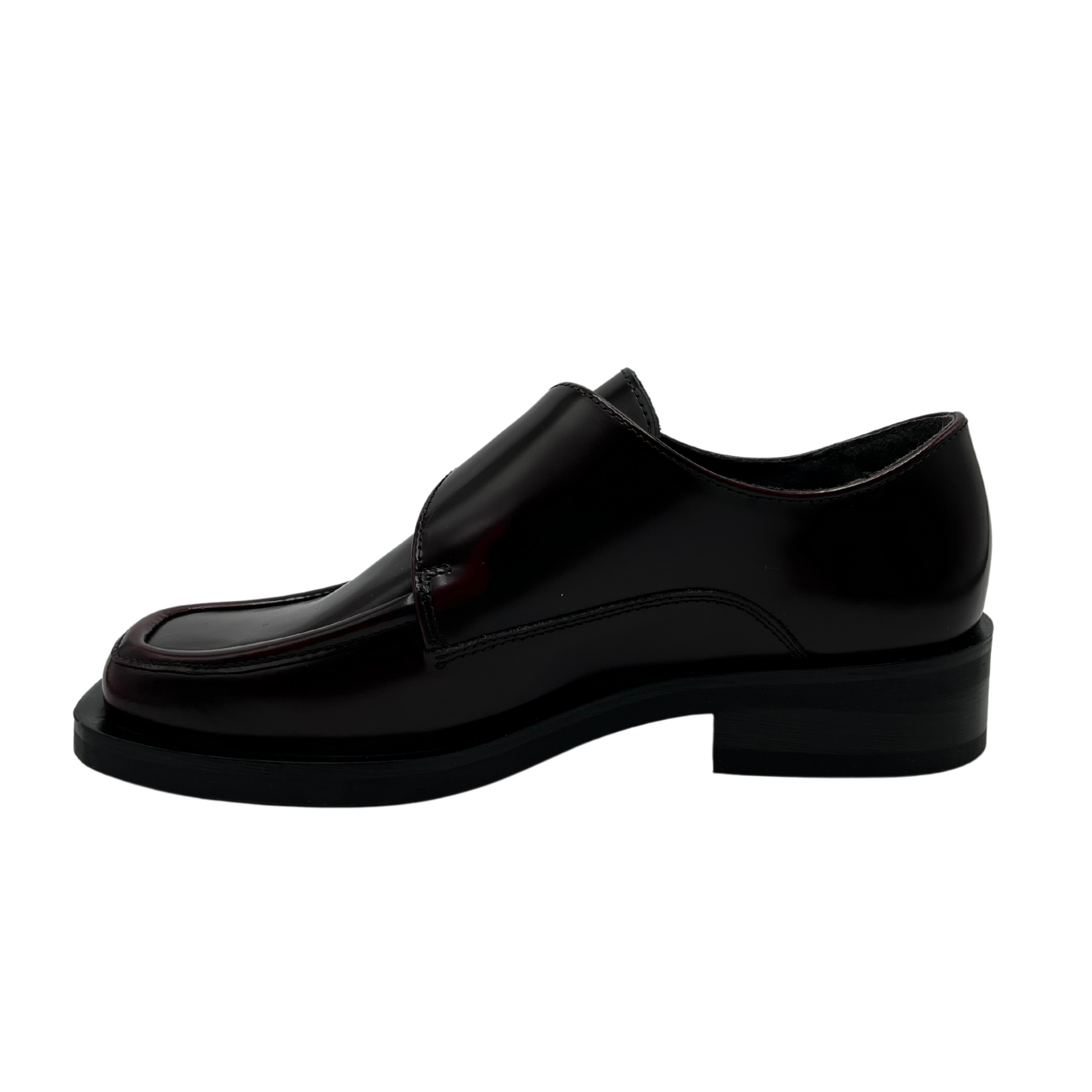 Left facing view of bordo leather loafer with silver buckle on upper, low heel and leather lining.