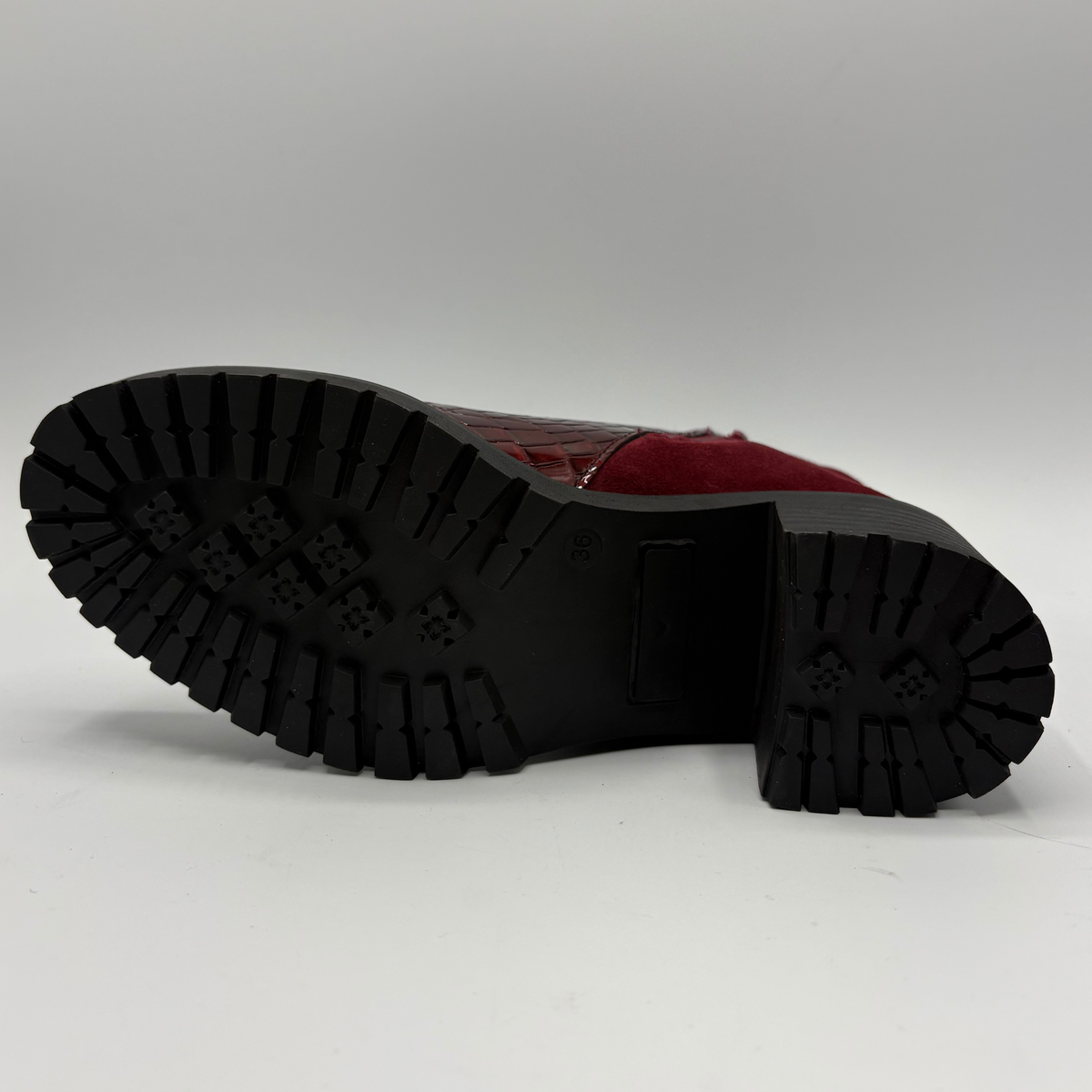 Bottom view of a short boot with a red croc front panel and a sturdy block heel