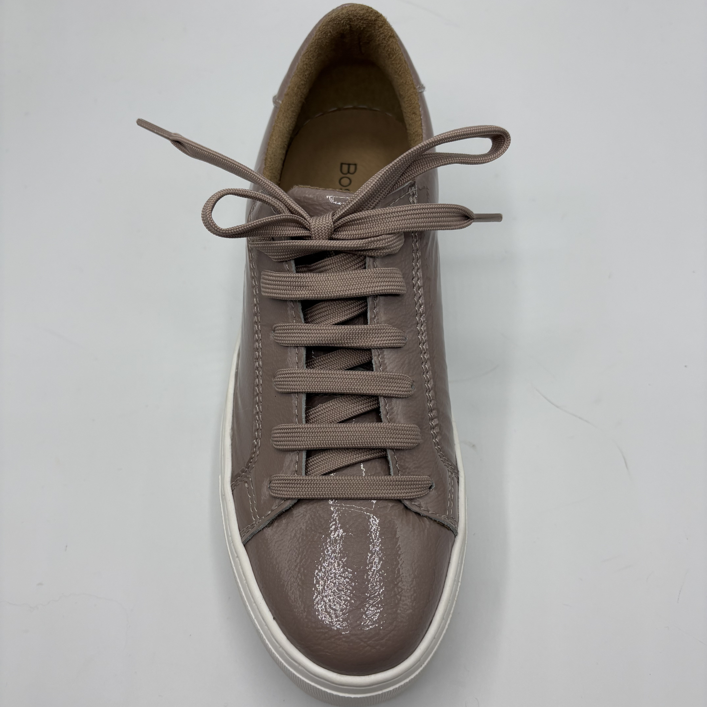Brown sneaker with white sole on a light gray background