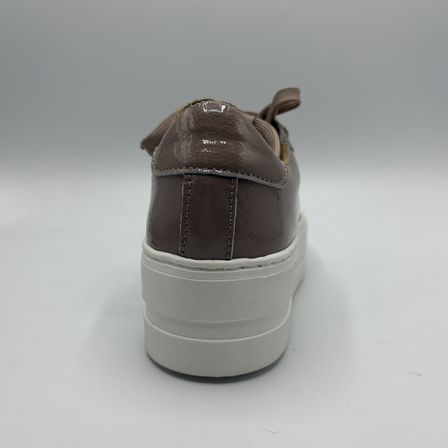 Brown sneaker with a white sole on a gray background