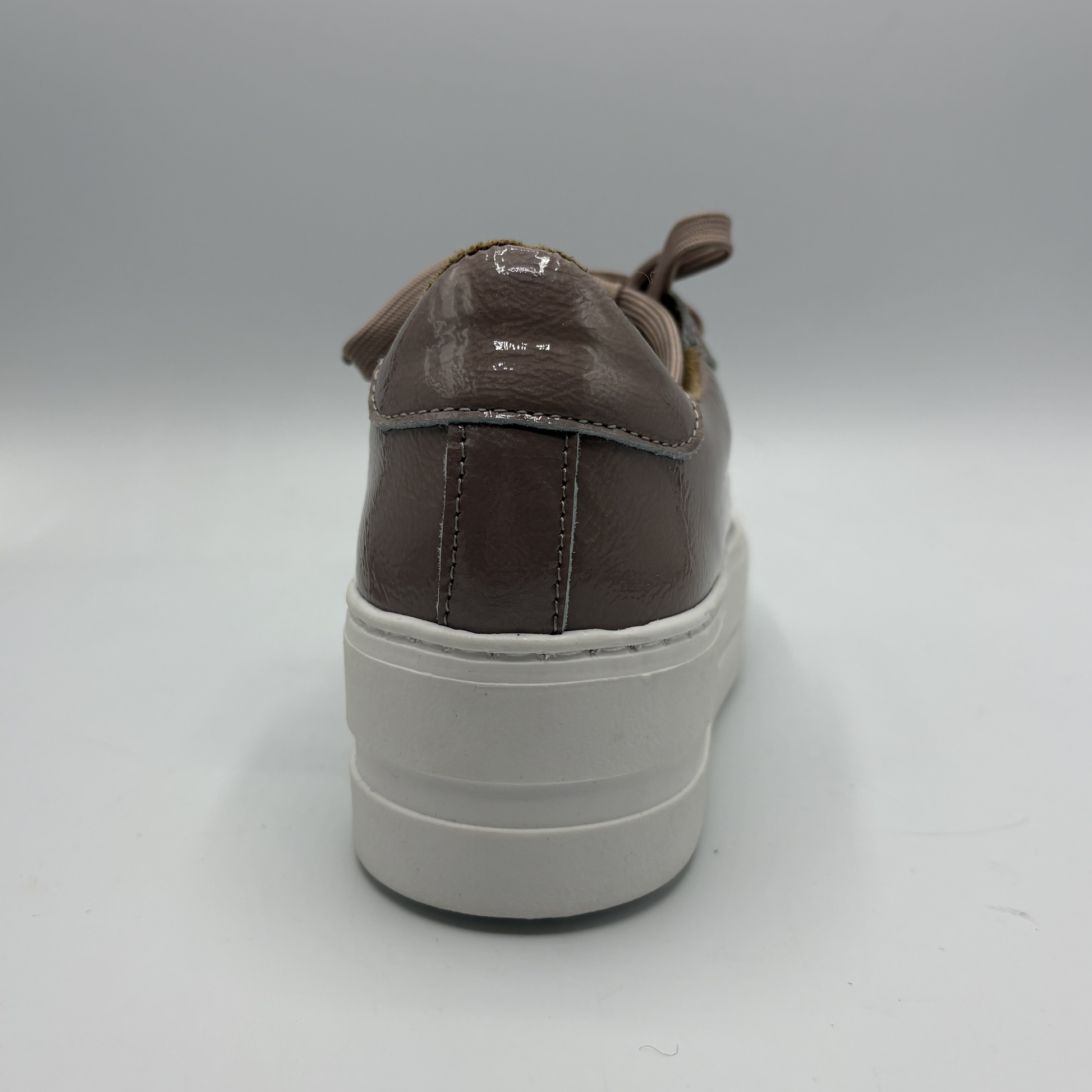 Brown sneaker with a white sole on a gray background