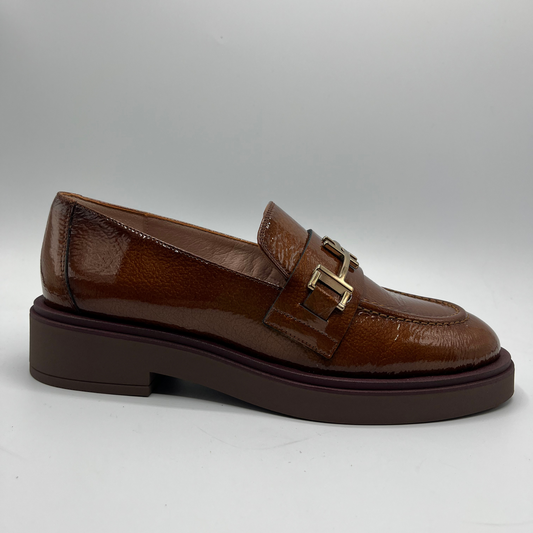 Brown leather loafer with a gold buckle on a gray background