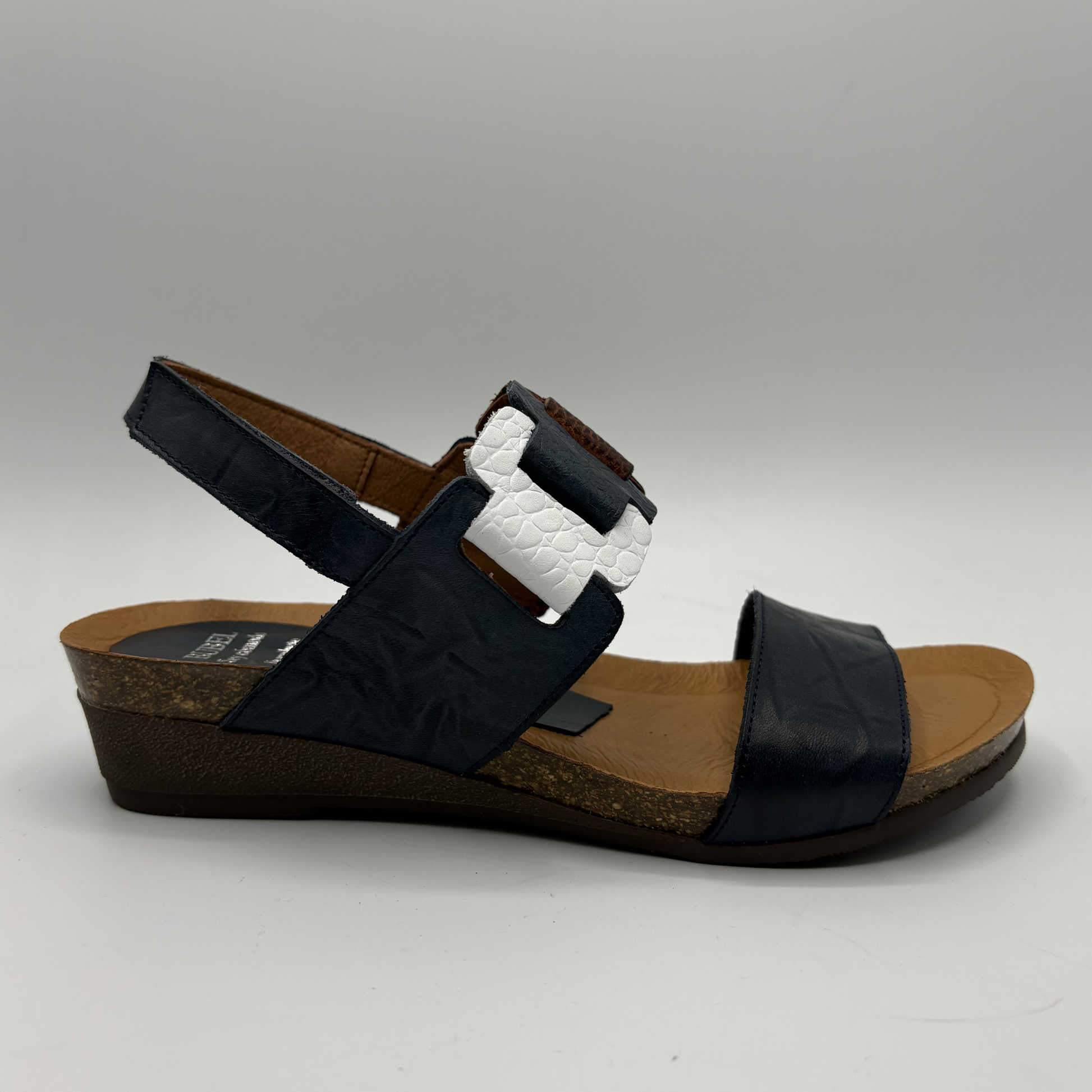 Black sandal with white strap on a gray background