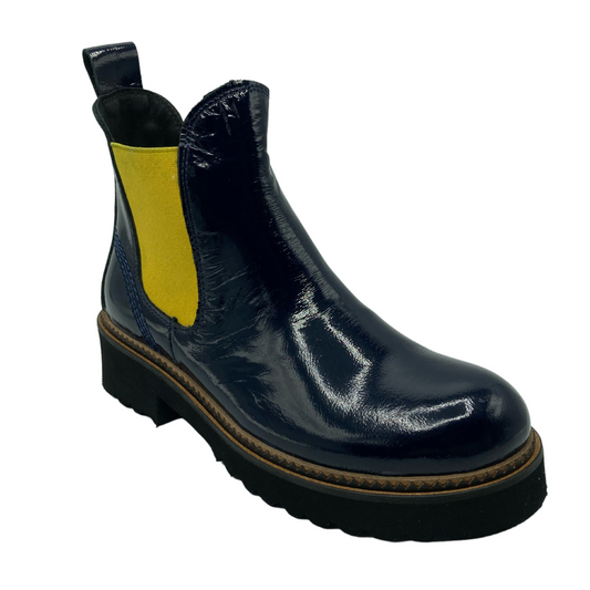45 degree angled view of navy patent leather ankle boot with yellow elastic gore and black lug sole