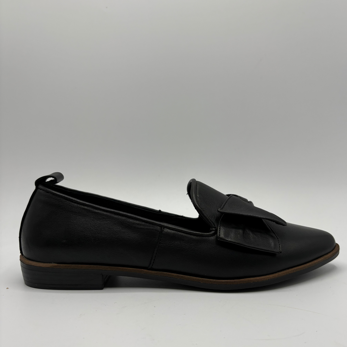 Right facing view of a black leather loafer with a bow accent on the toe box