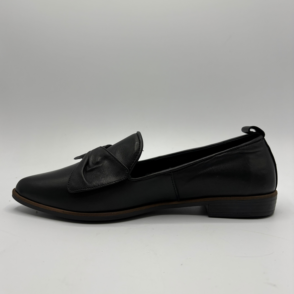 Left facing view of a black leather loafer with a bow accent on the toe box