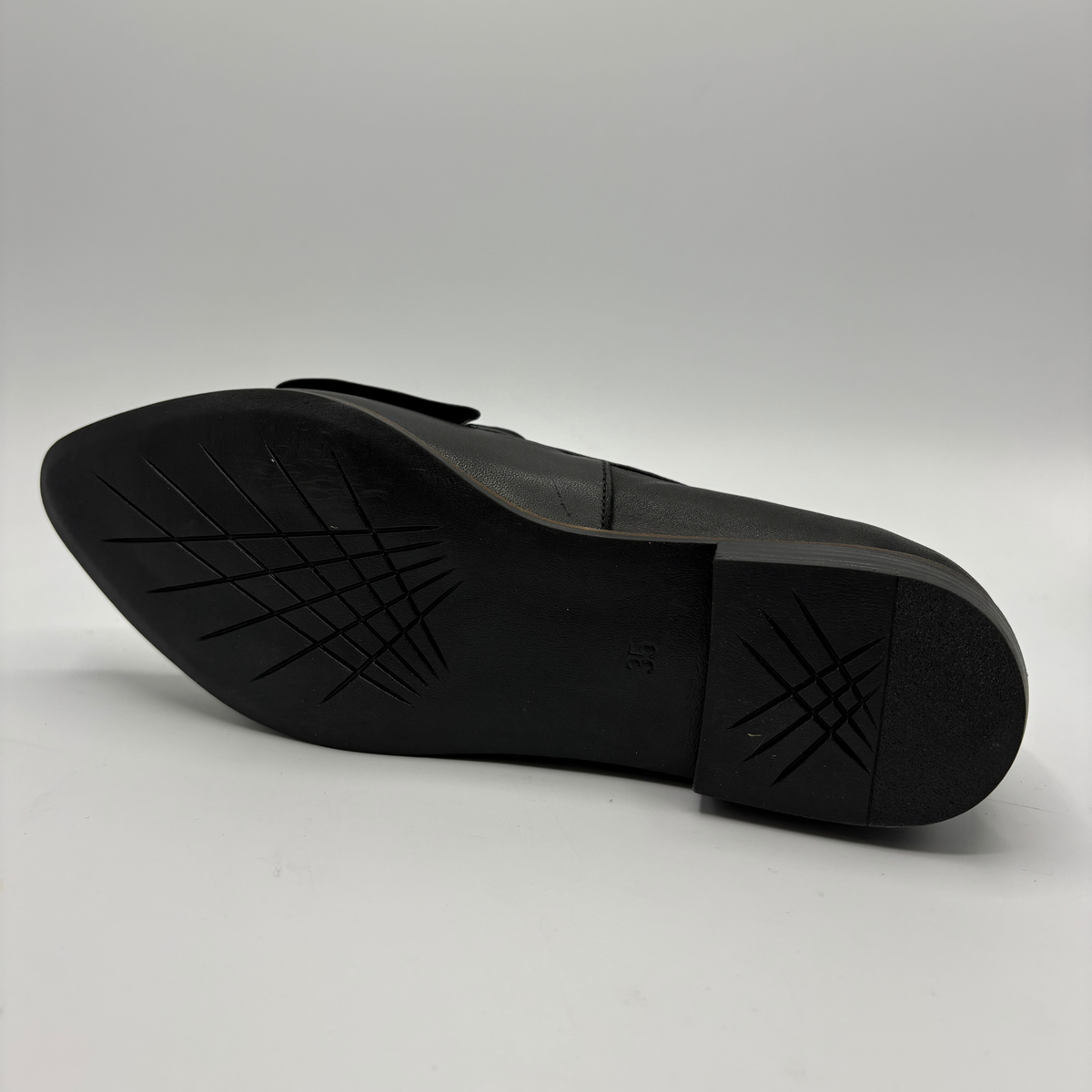 Bottom view of a black leather loafer with a bow accent on the toe box