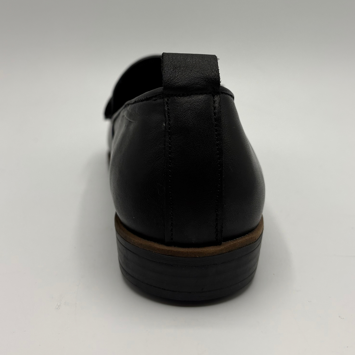 Back view of a black leather loafer with a bow accent on the toe box