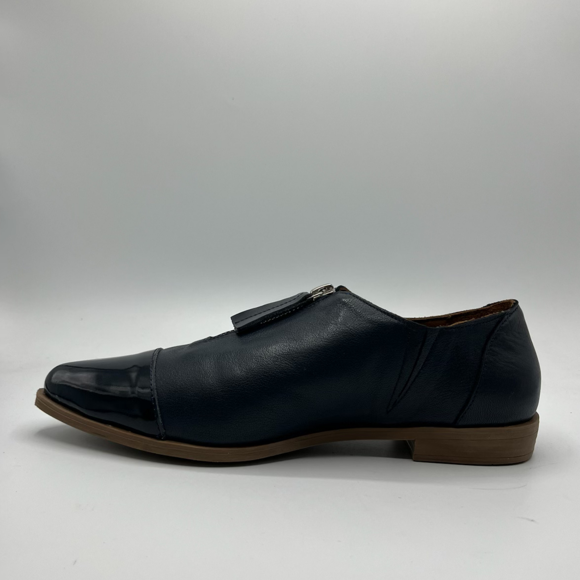 Navy leather shoe with a brown sole on a light gray background