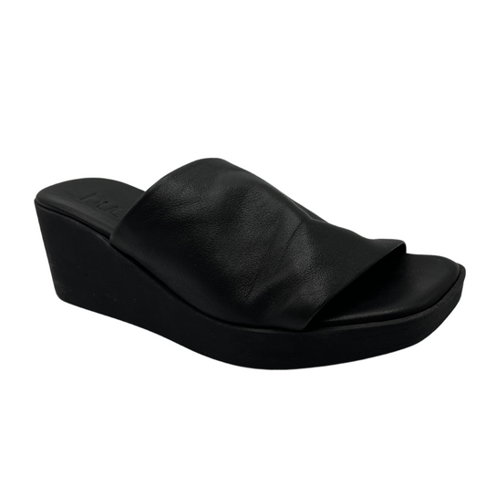 45 degree angled view of black leather wedge sandal with square toe and black outsole