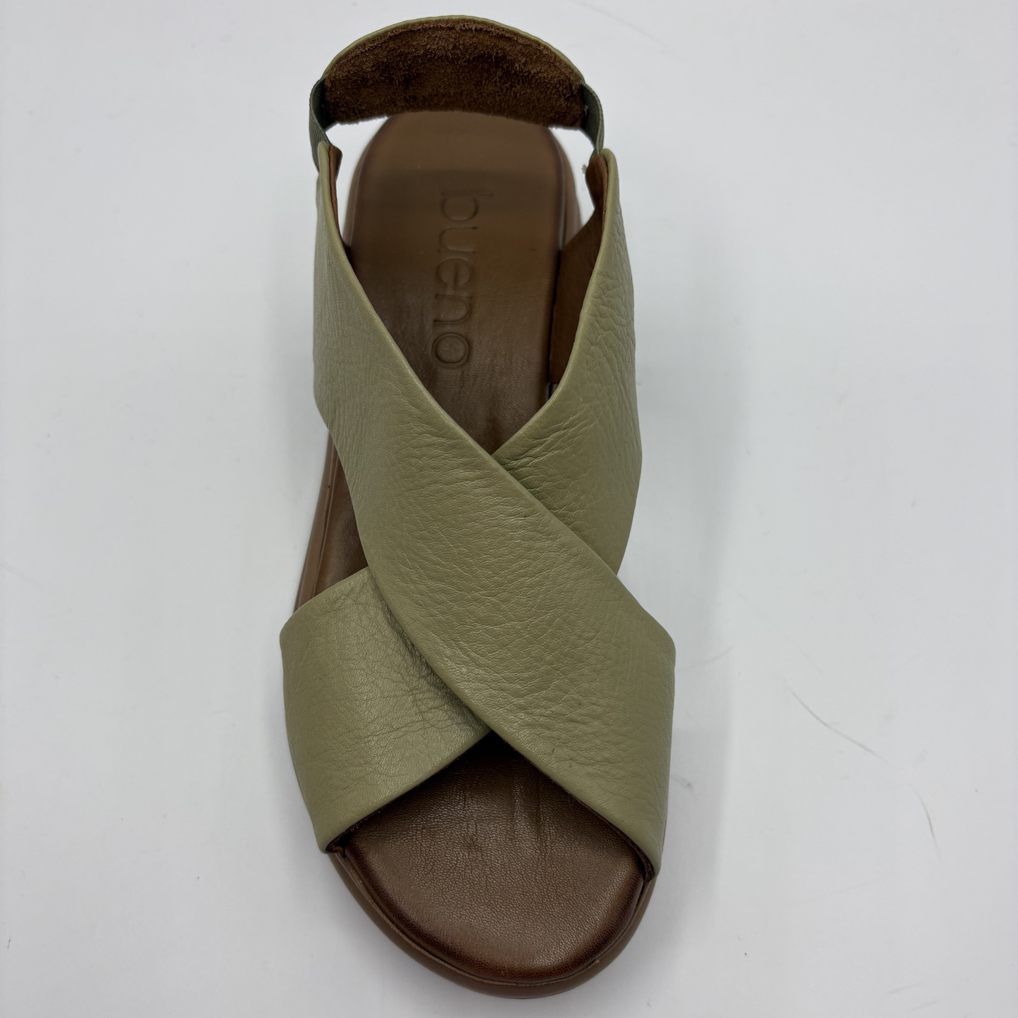 Green sandal with criss-cross strap design on a white background