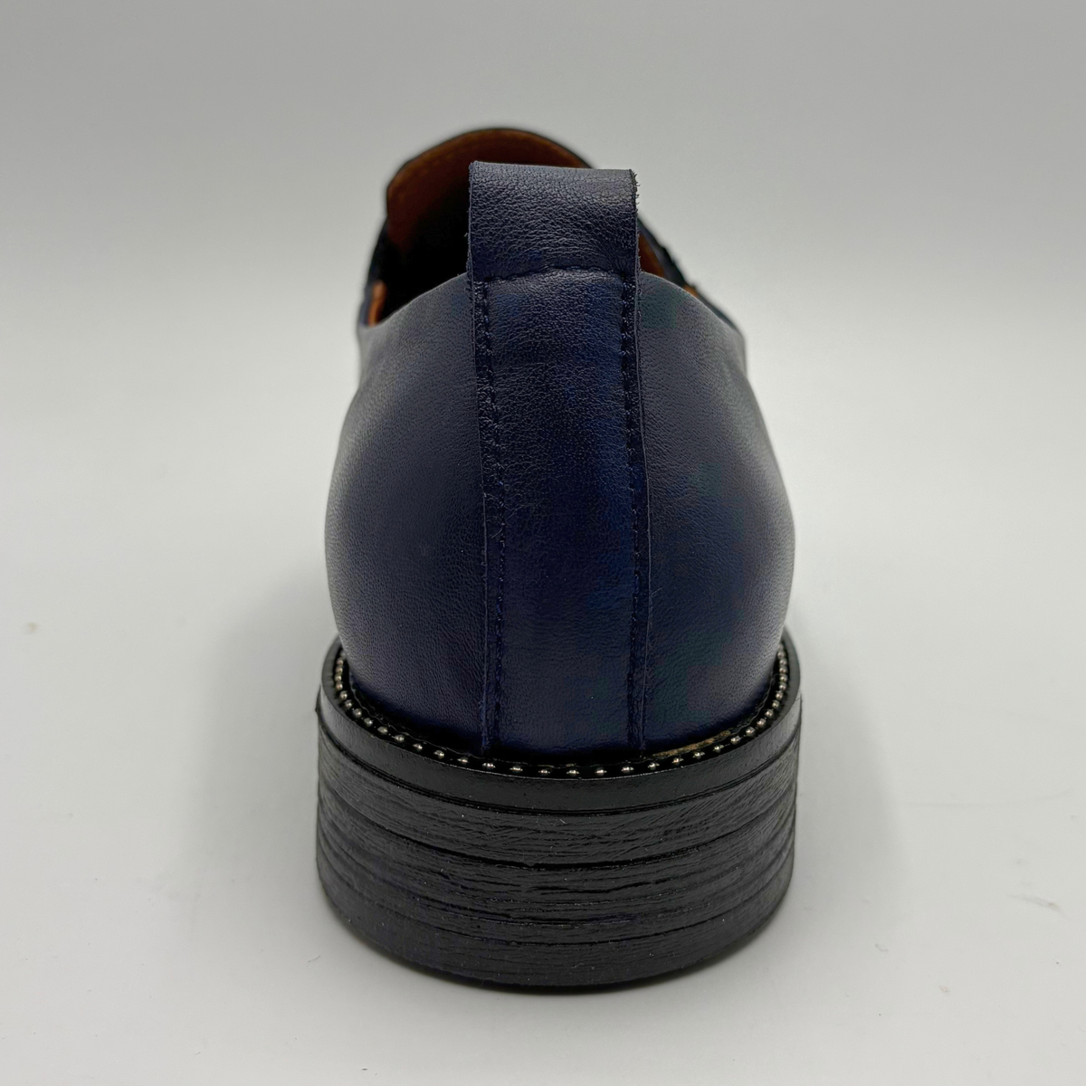 Back view of a navy leather loafer with a pull on heel tab
