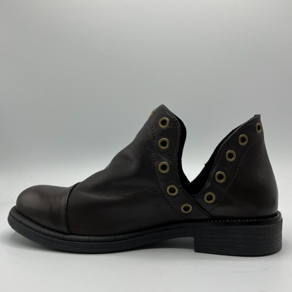 Black leather shoe with eyelets on a gray background