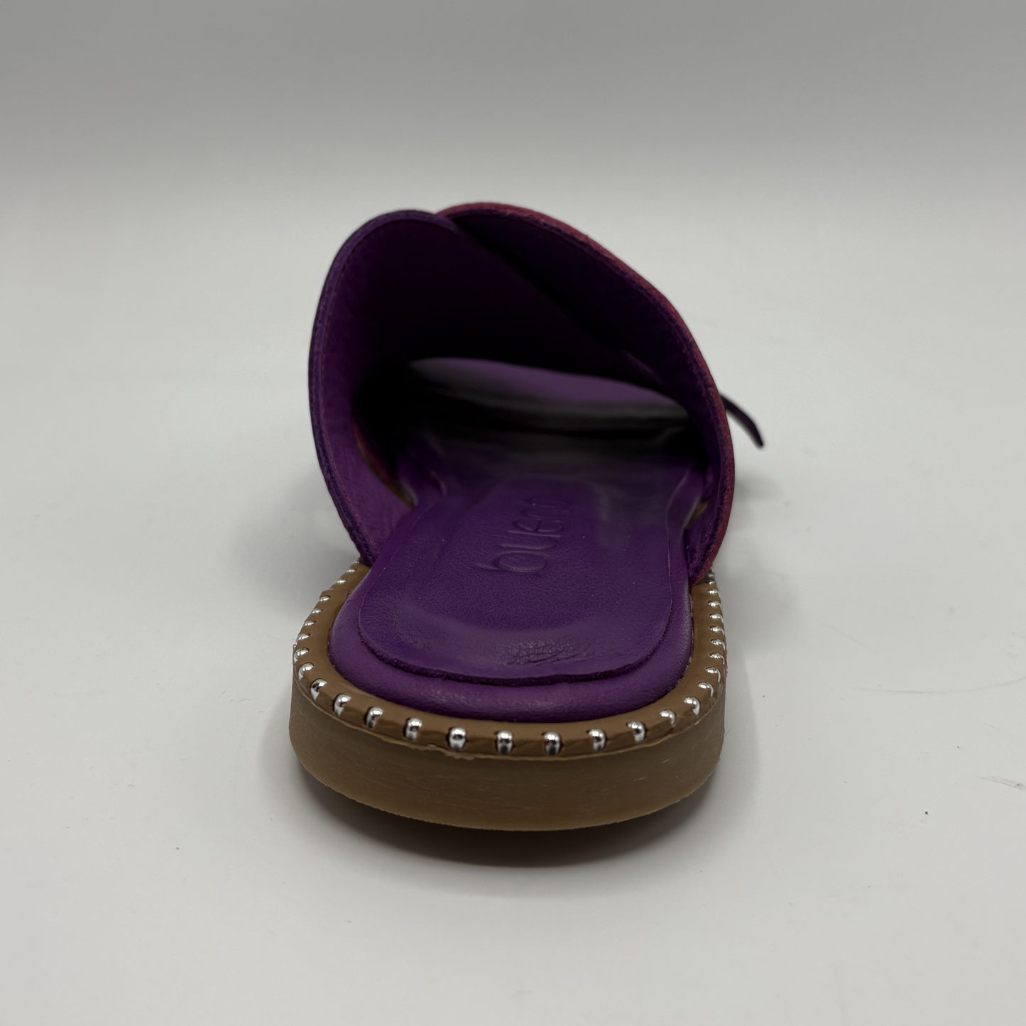 Purple sandal with studded detail on a gray background