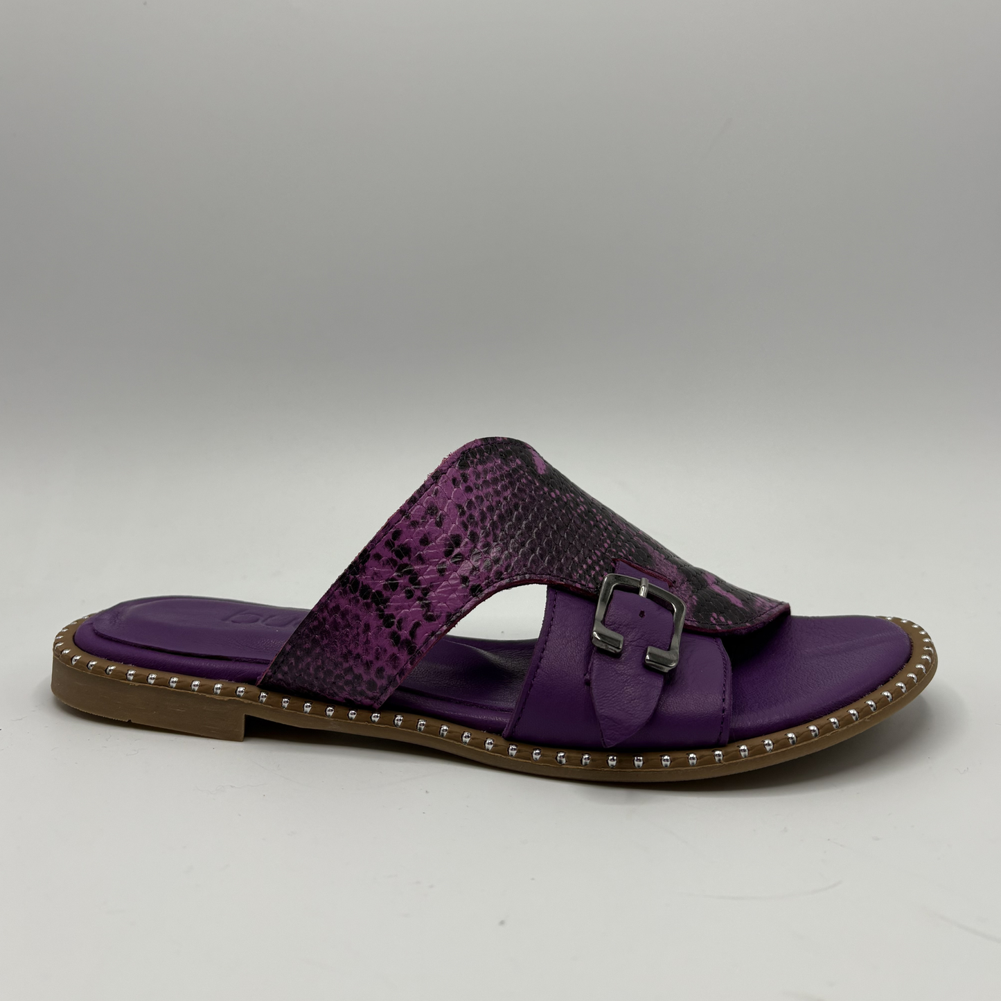 Purple sandal with a snake patterned strap and brown sole on a gray background