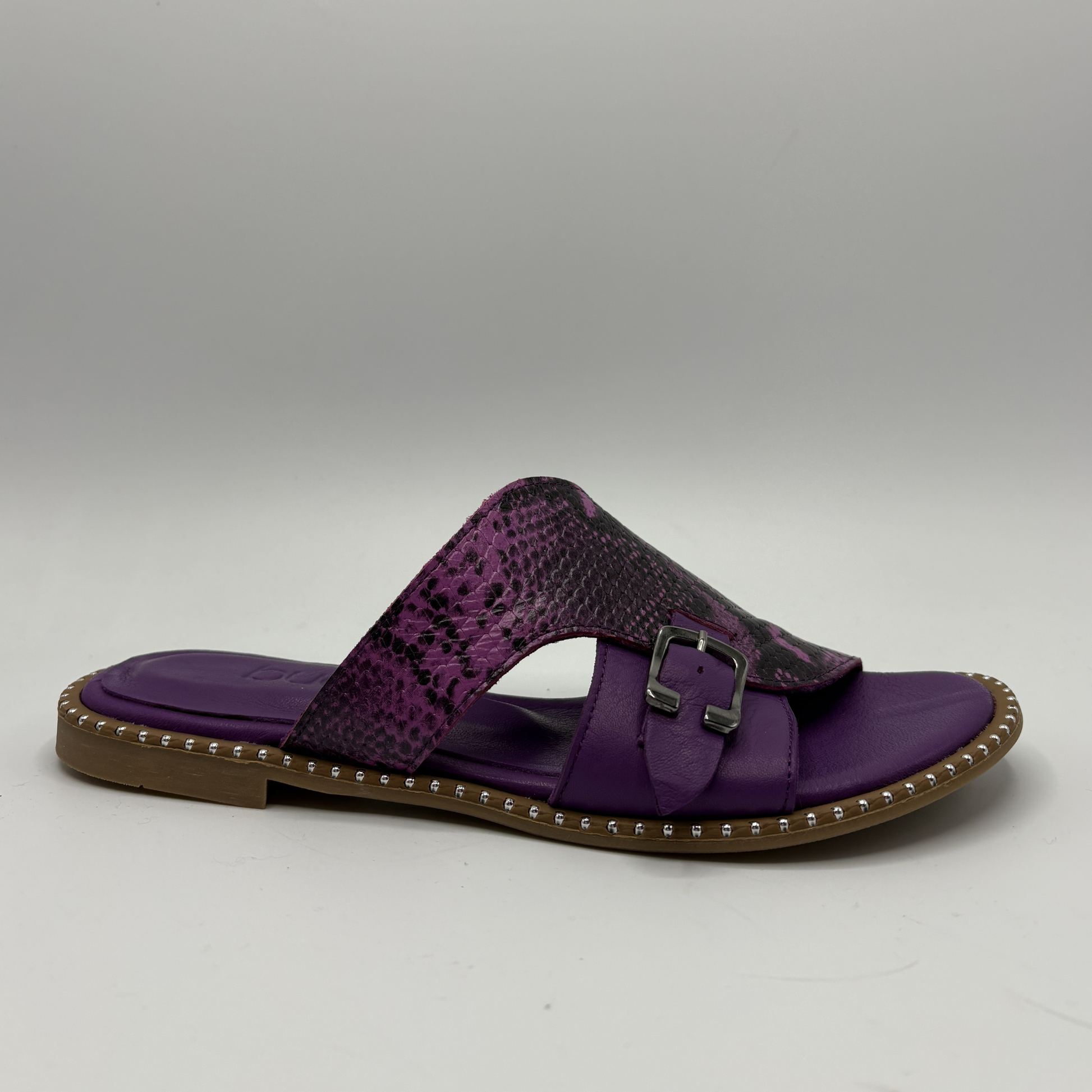 Purple sandal with a snake patterned strap and brown sole on a gray background