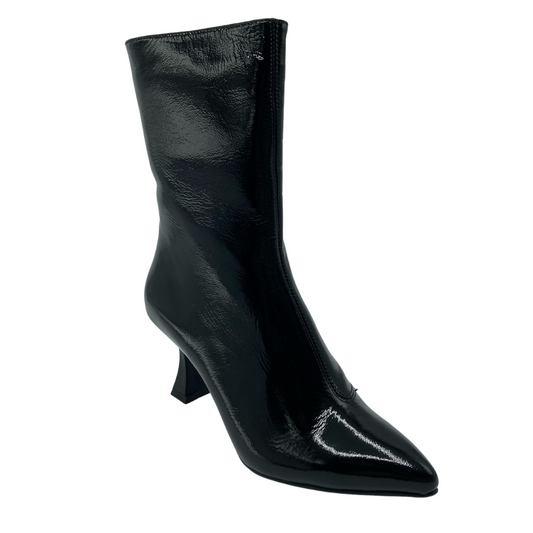 45 degree angled view of patent leather short boot with pointed toe and flared heel